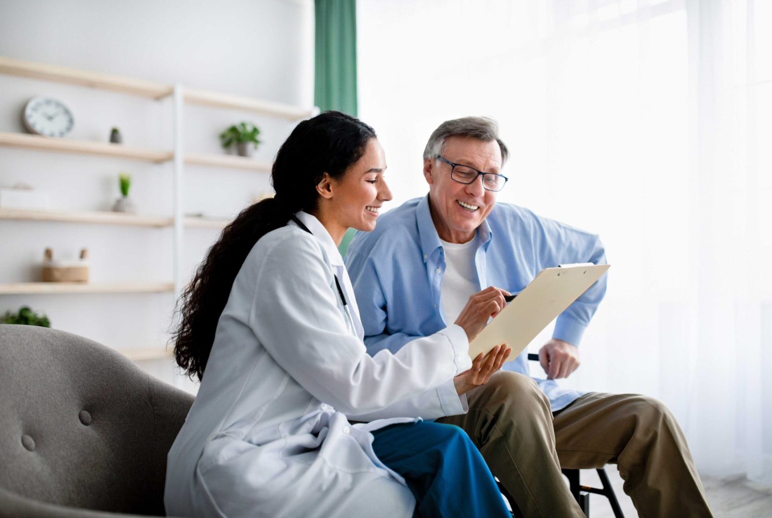 Image of a female doctor showing a patient him something on a clipboard that's making him smile.